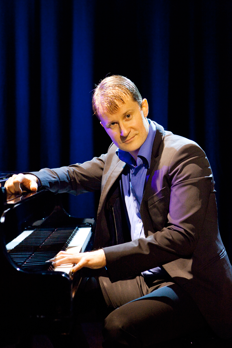 Pianisti Janne Maarala puvussa flyygelin ääressä vasen käsi koskettimistolla.