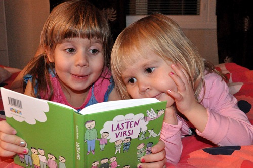 Kaksi lasta tutkii lasten virsikirjaa