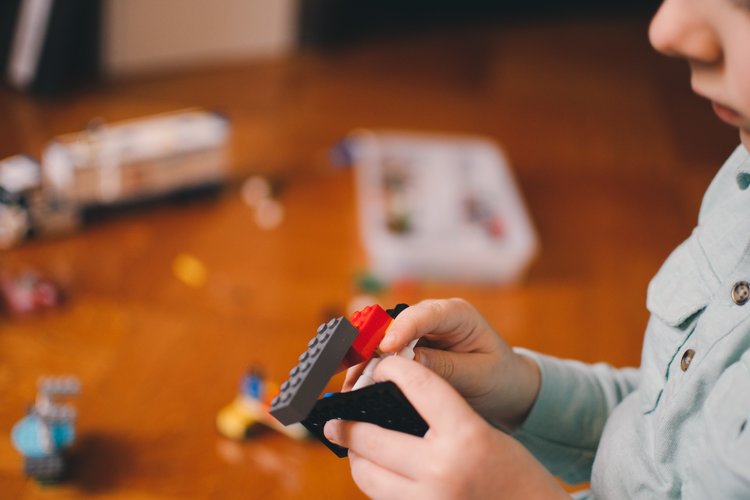 Poika rakentaa lego-palikoista rakennelmaa.