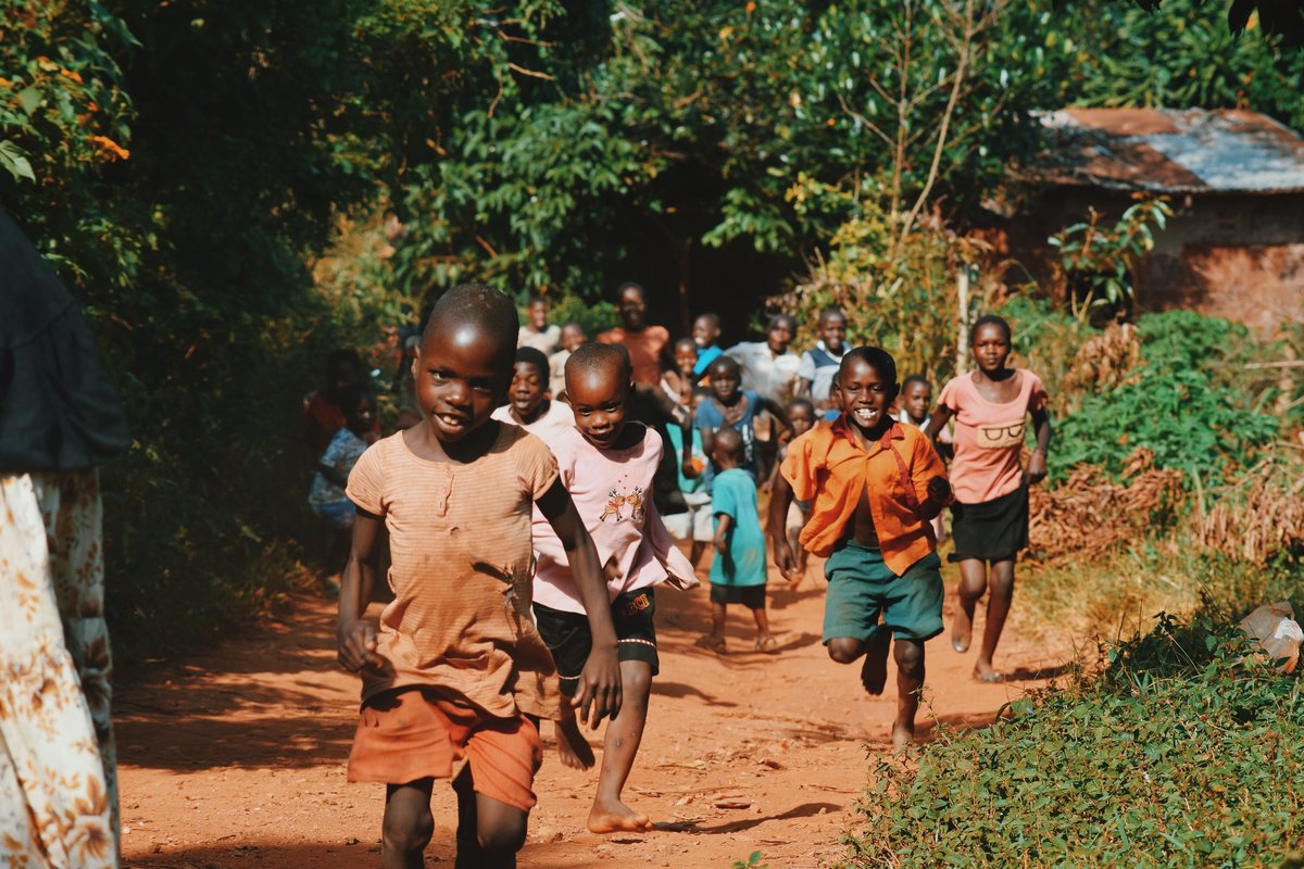 Afrikkalaiset lapset juoksevat kohti pitkin kylätietä.