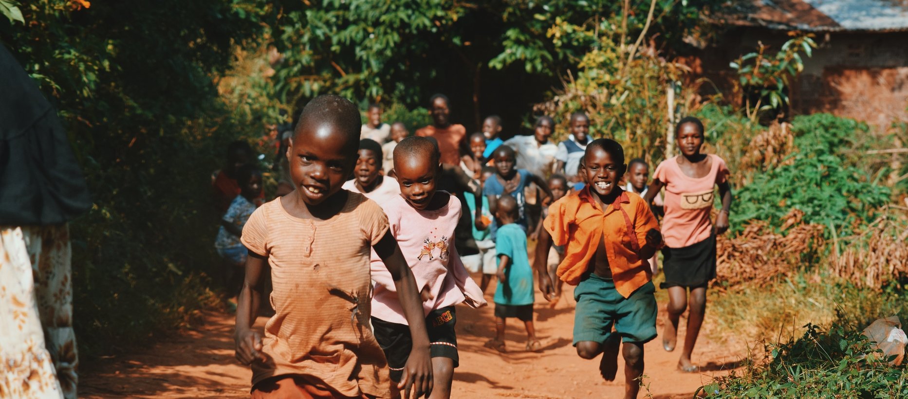Afrikkalaiset lapset juoksevat kohti pitkin kylätietä.
