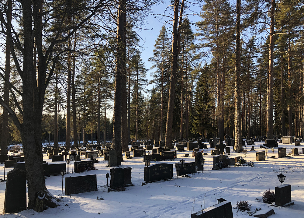 Pötönkankaan hautausmaa talvella aurinkoisena päivänä: paljon puita ja hautakiviä.